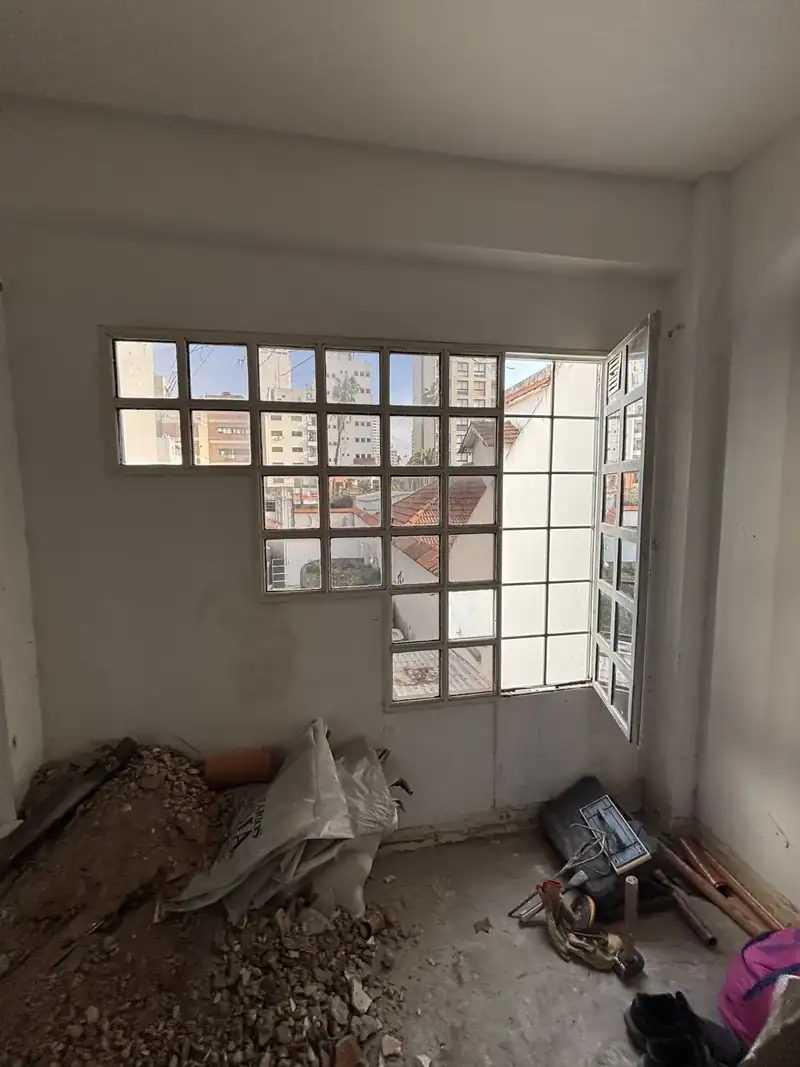 Ambiente en demolición con escombro en el piso y ventana de bloques de vidrio