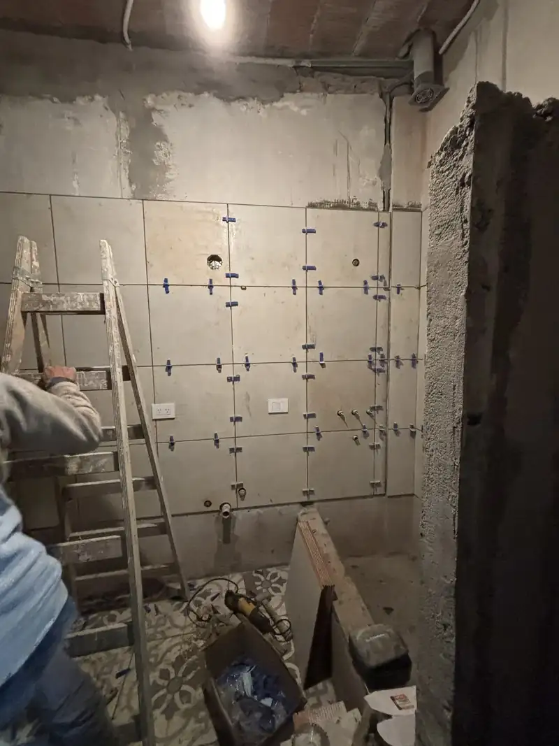 Pared de baño con porcelanato de gran formato en colocación, con niveladores
