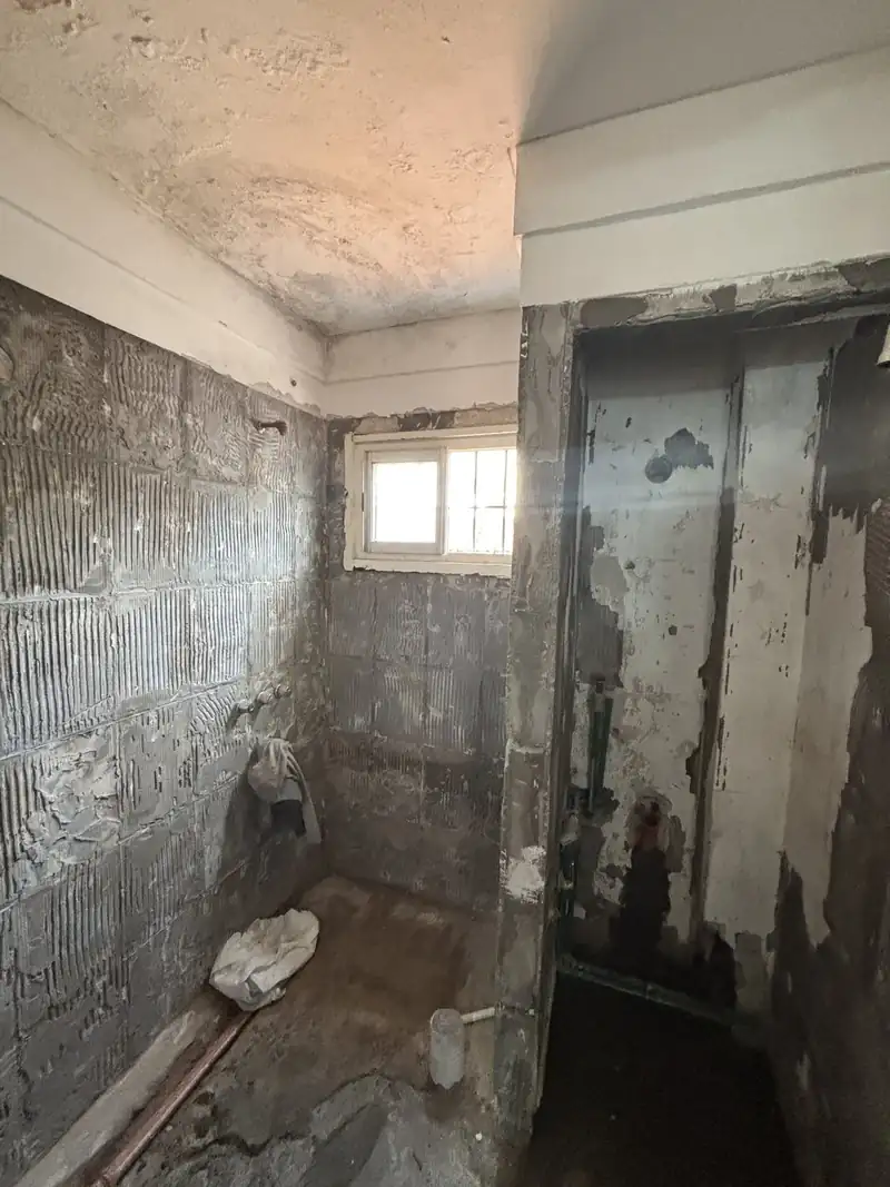 Baño con el revestimiento viejo retirado, antes de la reforma