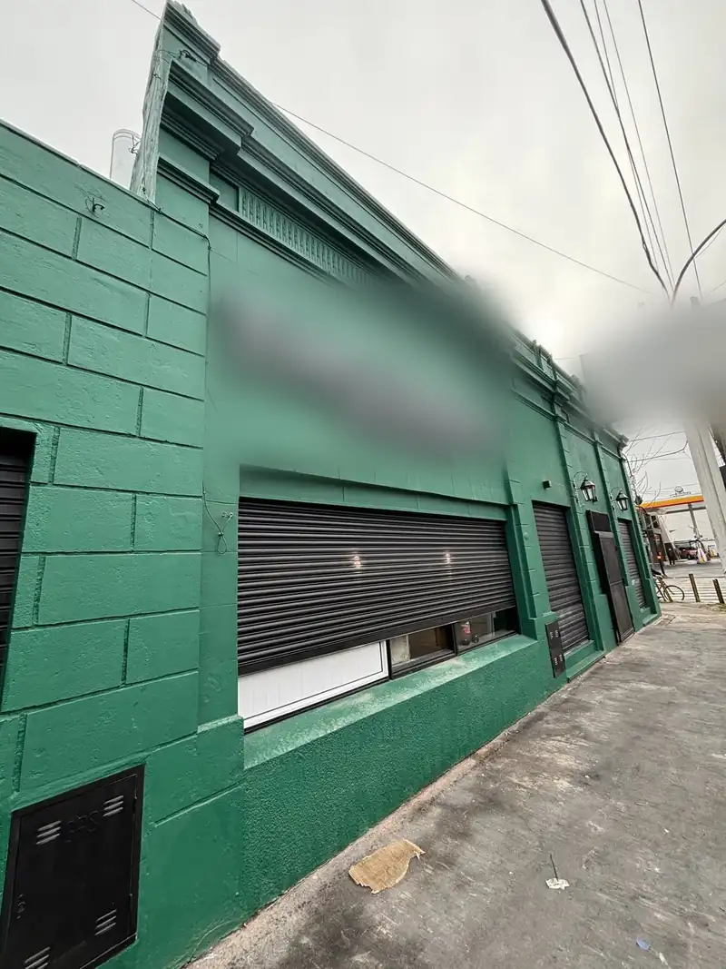 El mismo frente de local ya reparado y pintado de verde, con zócalo oscuro