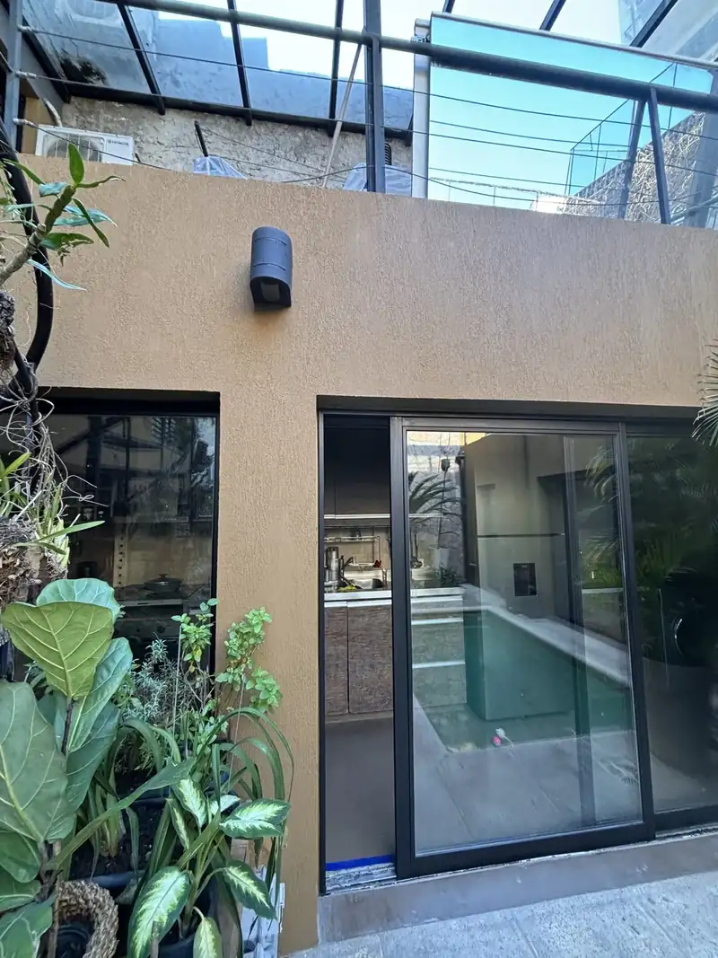 Patio con pileta, plantas y muro con revestimiento texturado después de la obra