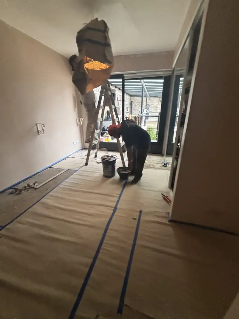 Pintores trabajando en un ambiente con el piso cubierto con cartón y cinta de pintor