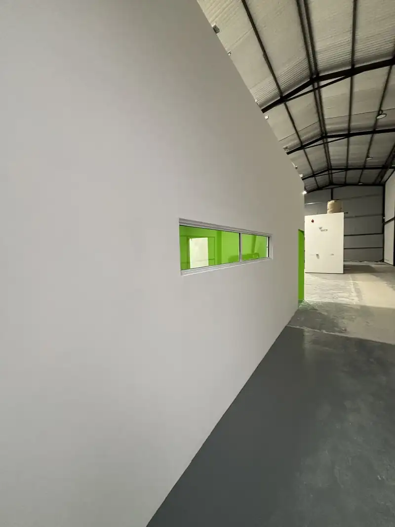 Tabique de placa de yeso terminado y pintado de gris claro, con una ventana interior angosta