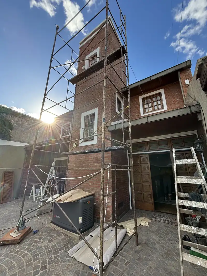Torre de ladrillo de una casa en refacción, con andamio armado durante la restauración de la fachada